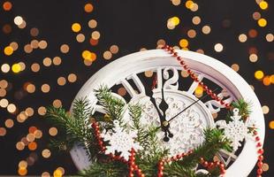 feliz año nuevo a la medianoche de 2018, viejo reloj de madera con luces navideñas y ramas de abeto foto