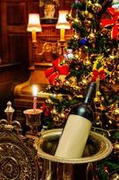 botella de vino en la celebración navideña. decoración de la sala de estar en diciembre festivo, temporada de invierno. hermoso fondo interior de la habitación de adorno de luz dorada.
