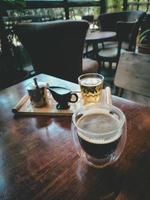 Black coffee on wood table, gray wood background. Espresso glass beverage. Arabica drink prepare by Italian barista. Hot caffeine cup in morning cafe. Natural light photo, nobody. photo