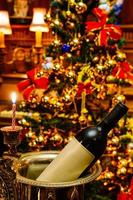botella de vino en la celebración navideña. decoración de la sala de estar en diciembre festivo, temporada de invierno. hermoso fondo interior de la habitación de adorno de luz dorada. foto