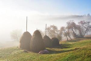 increíble paisaje montañoso con niebla y un pajar en otoño foto