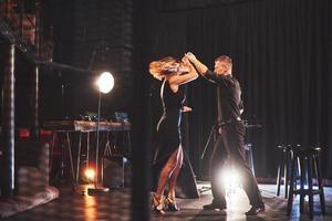 hábiles bailarines actuando en el cuarto oscuro bajo la luz foto