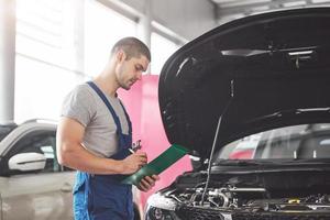 Portrait of a mechanic at work in his garage - car service, repair, maintenance and people concept photo