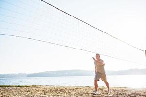 un hombre atlético mirando la costa en la playa de arena salvaje. hombre masculino y deportivo con torso desnudo está haciendo entrenamiento nocturno a la costa del mar. entrenamiento de verano al aire libre foto