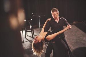 hábiles bailarines actuando en el cuarto oscuro bajo la luz foto