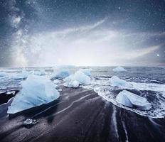 icebergs flotando en el lago glacial jokulsarlon. sur de islandia laguna. noche de cielo estrellado. fantástica vía láctea. foto