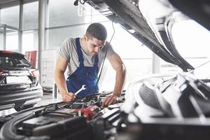 Imagen que muestra un trabajador de servicio de coche musculoso reparando el vehículo foto