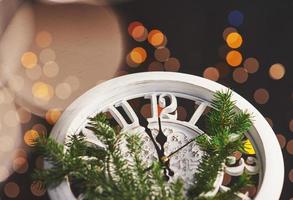 feliz año nuevo a la medianoche de 2018, viejo reloj de madera con luces navideñas y ramas de abeto foto