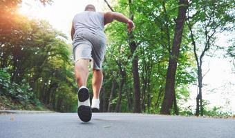 carrera a campo traviesa al aire libre en concepto de ejercicio, fitness y estilo de vida saludable. cerca de los pies del joven corredor corriendo por la carretera en el parque foto