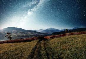 paisaje de verano de montaña. hierba alta y cielo nocturno vibrante con estrellas y nebulosa y galaxia. astrofotografía de cielo profundo foto