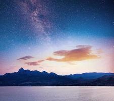 magnificent panorama of sunrise over the sea. Vibrant night sky with stars and nebula and galaxy. Deep sky astrophoto