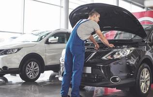 Imagen que muestra un trabajador de servicio de coche musculoso reparando el vehículo foto