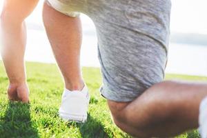 correr a campo traviesa al aire libre en el concepto de sol de verano para hacer ejercicio, estar en forma y un estilo de vida saludable. cerca de los pies de un hombre corriendo en la hierba foto