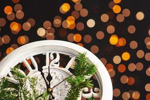 feliz año nuevo a la medianoche de 2018, viejo reloj de madera con luces navideñas y ramas de abeto foto