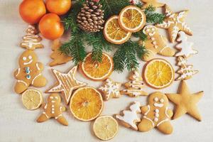 Christmas gingerbread cookies and dried orange and spices on white table. Chairs Christmas trees, cones and Christmas decorations photo