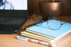 close up of notepad, pen and laptop on table photo