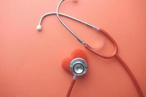 heart shape symbol and stethoscope on red background photo