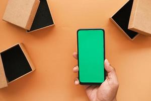 hand using smart phone with green screen and empty gift box on table photo