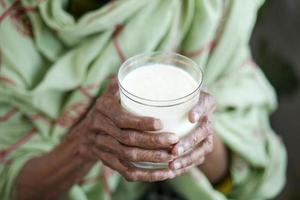 senior women hand holding glass of milk at early morning photo