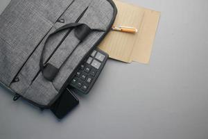 Top view of note pad, calculator, pen in a office bag on gray background photo