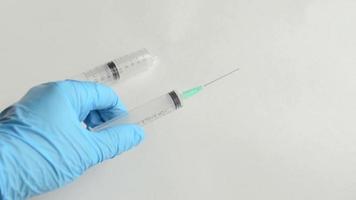 o médico segura e coloca na superfície branca uma seringa em uma luva médica para vacinação contra coronavírus. video