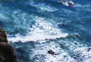 Aerial view from above of ocean, rocks and water waves in Pacific ocean.