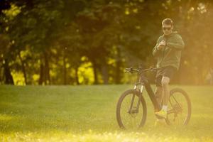 Young man checking time on ebike in nature photo
