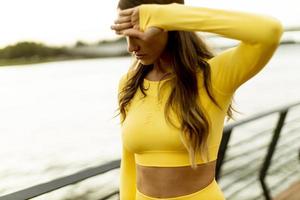 Young woman taking a break during exercise on the riverside pier photo