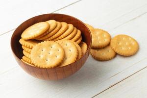 Galletas de galleta redondeadas en un recipiente de madera sobre fondo de mesa de madera blanca foto