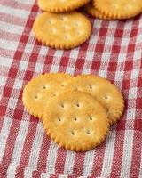 Galletas cracker con mantel sobre fondo de mesa de madera blanca foto