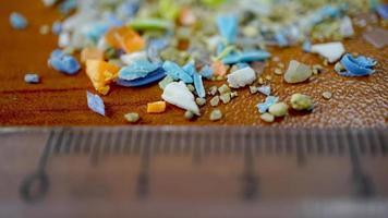 Macro shot of authentic real microplastic particles gathered from the beach with a ruler to show their size. Water pollution and global warming concept. photo