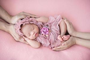 father and mother hand holding sleeping newborn baby photo