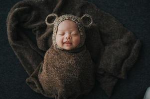 Happy newborn baby wrapped in cocoon photo