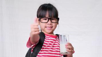 Cute schoolgirl drinking milk from a glass before going to school. Healthy nutrition for children. back to school concept