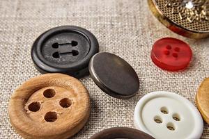 Sewing buttons of various sizes and colors on sackcloth. photo