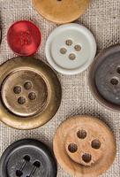 coser botones de varios tamaños y colores en tela de saco. foto