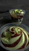 The photo is a photo of avocado-flavored ice cream in a cup with a black background