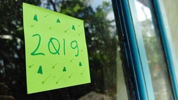 2019 text photo with green paper on house window glass background