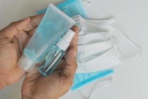 gel de lavado de manos azul y spray de manos con máscara sobre fondo blanco para limpiar y prevenir los gérmenes de los virus foto
