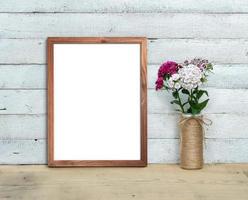 Vertical A4 Old Wooden Frame mockup near a bouquet of sweet-william  stands on a wooden table on a painted white wooden background. Rustic style, simple beauty. 3d render. photo