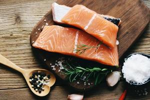 Raw salmon filet with herbs and spices on wooden background photo