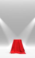 podio, pedestal o plataforma cubierta con tela roja iluminada por focos sobre fondo blanco. ilustración abstracta de formas geométricas simples. representación 3d foto