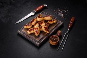 Grilled sausages with spices on a dark stone background photo
