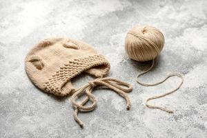 Baby knitted beige clothes on a white concrete background photo