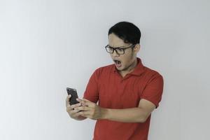 Wow face of Young Asian man shocked what he see in the smartphone on isolated grey background. photo