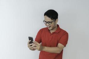 Young Asian man shocked and happy with what he see in the smartphone on isolated grey background. photo