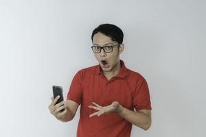 Wow face of Young Asian man shocked what he see in the smartphone on isolated grey background. photo