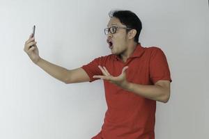 Wow face of Young Asian man shocked what he see in the smartphone on isolated grey background. photo