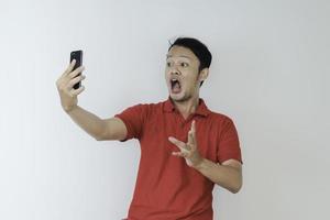 Wow face of Young Asian man shocked what he see in the smartphone on isolated grey background. photo