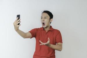 Wow face of Young Asian man shocked what he see in the smartphone on isolated grey background. photo